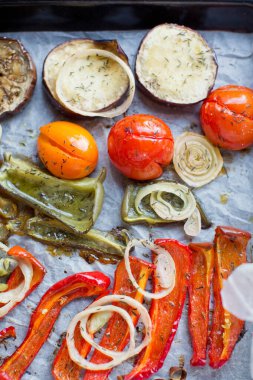 Fırında patlıcan, domates, soğan, biber ve bitkilerle dolu tepsi.