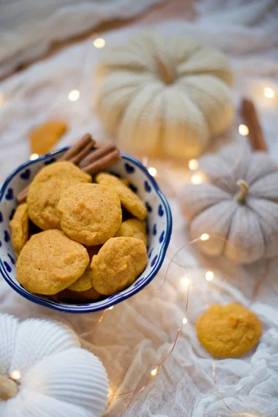 Tasty pumpkin cookies in a bowl with cinnamon, pumpkin decorations and lights