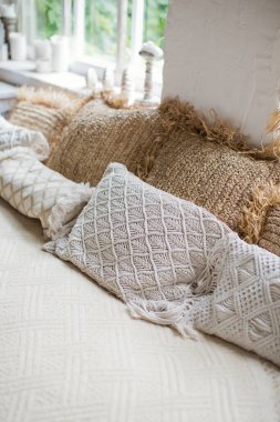 Kaliteli boho detayları ve büyük pencereleri olan açık renkli yatak odası.