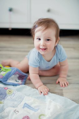 Mavi elbiseli şirin beyaz bebek oyuncaklarla oynuyor.