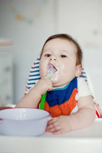 小さな男の子はミルクのお粥を食べる かわいいビブで赤ちゃんはミルク粥を食べる — ストック写真