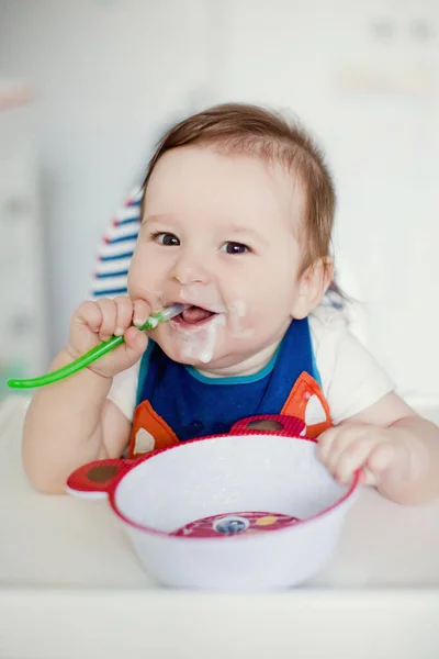 小さな男の子はミルクのお粥を食べる かわいいビブで赤ちゃんはミルク粥を食べる — ストック写真