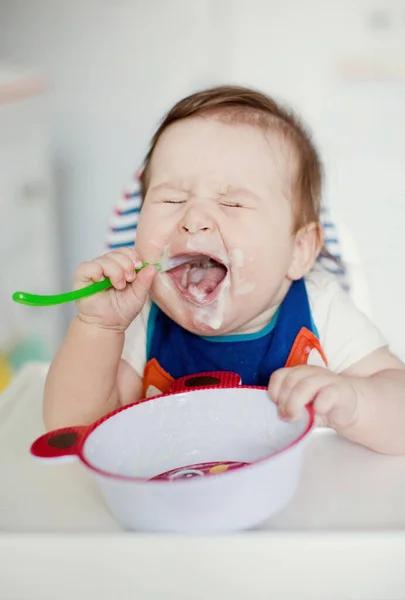 小さな男の子はミルクのお粥を食べる かわいいビブで赤ちゃんはミルク粥を食べる — ストック写真