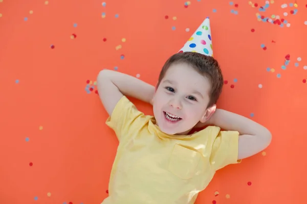 Maluch Biały Chłopiec Kapeluszu Urodzinowym Czerwonym Papierze Tle Kolorowym Konfetti — Zdjęcie stockowe