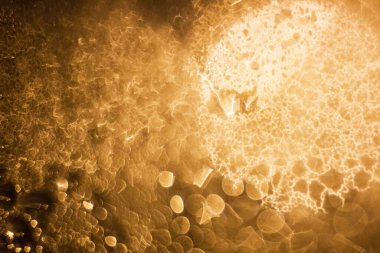 Cam pencereye yağmur damlaları düşer. Dışarıda turuncu ışık var.