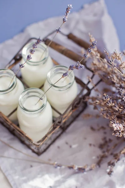 Vintage Glazen Flessen Met Melk Lavendelbloemen Een Blauwe Achtergrond — Stockfoto