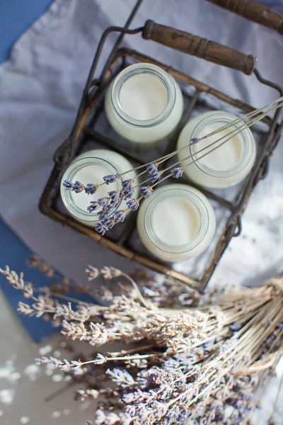 Vintage glass bottles with milk and lavender flowers on a blue background