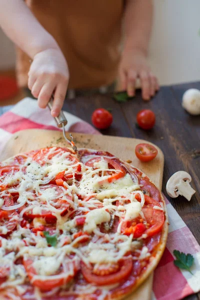 Child make homemade pizza with salami, onion, tomato and cheese. Little helper and homemade pizza