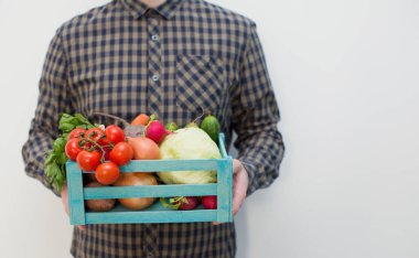 Mavi tahta bir kutuda taze sebzeler. Yemek servisi. Adamın elinde sebzeli mavi tahta kutu var.