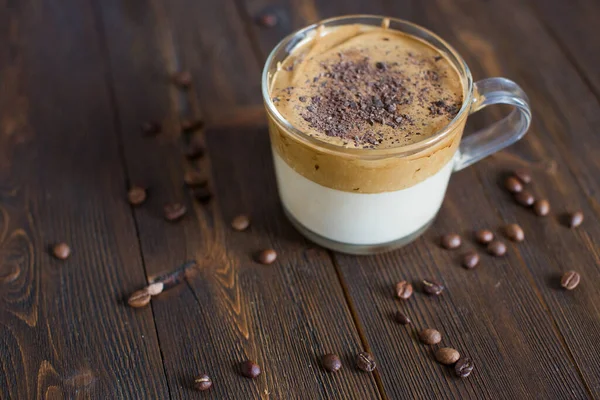 アイス ダルゴナ コーヒーとチョコレートパウダーをグラスカップに入れて トレンディふわふわのクリーミーなホイップコーヒー 木の背景にコーヒー — ストック写真