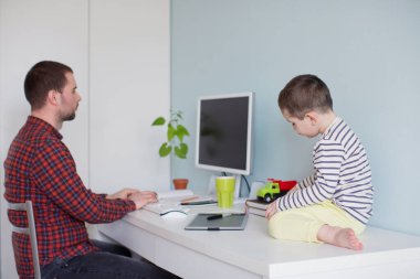 COVID-19 karantinası sırasında çocuklarla evde çalışmak. Küçük oğlu dikkatini dağıtırken genç babası çalışmaya çalışıyor.