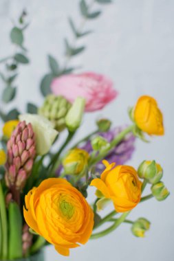 Turuncu ve pembe ranunculus çiçekli güzel bir buket, okaliptüs ve beyaz arkaplanda yeşil bir vazoda sümbül.