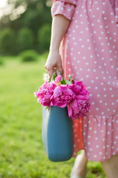 女性は青い袋の中にピンクの牡丹と公園を歩く — ストック写真
