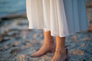 Gün batımında beyaz bir elbiseyle dans eden genç bir kadın.