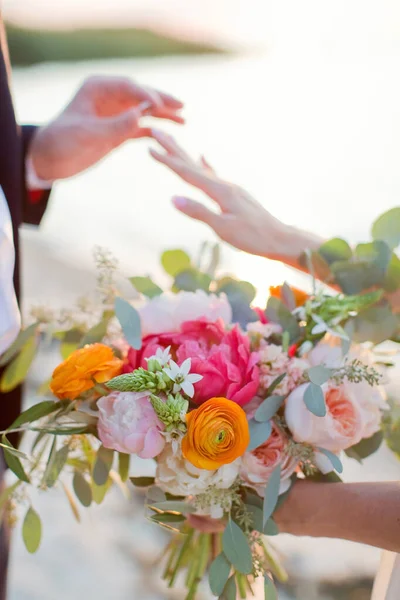 新郎は海の近くの日没時に花嫁の手に結婚指輪を置きます — ストック写真