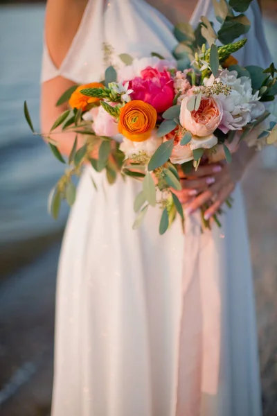 花嫁は美しい花とピンクのシルクリボンと結婚式の花束を保持します 海の近くに立っている花の若い女性 — ストック写真