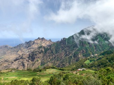 Güneşli bir günde Anaga Kırsal Parkı 'ndaki dağların panoramik manzarası beyaz bulutlar ve arka planda okyanus, Tenerife - Kanarya Adaları