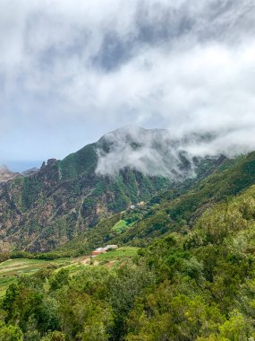 Güneşli bir günde, Anaga Kırsal Parkı 'ndaki dağlarda beyaz bulutlar ve arka planda okyanus, Tenerife - Kanarya Adaları