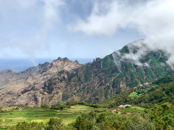 Güneşli bir günde Anaga Kırsal Parkı 'ndaki dağların panoramik manzarası beyaz bulutlar ve arka planda okyanus, Tenerife - Kanarya Adaları