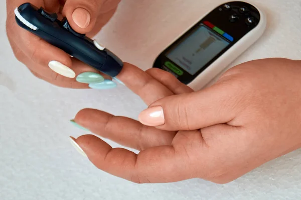 Şeker hastası kan şekerini ölçer. Kadın evinde bir mızrak ve glukometreyle kendini test ediyor..