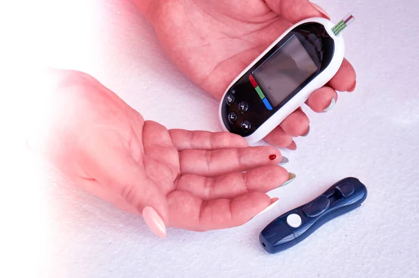 A diabetic checks his blood sugar. The woman is self-tested with a Lancet and a glucometer at home. — Stock Photo, Image