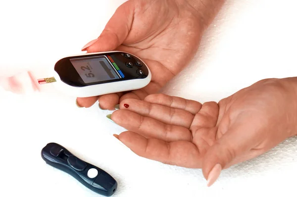 A diabetic checks his blood sugar. The woman is self-tested with a Lancet and a glucometer at home. — Stock Photo, Image