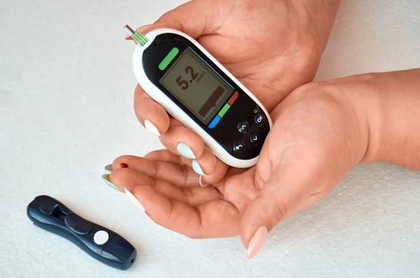Egy cukorbeteg ellenőrzi a vércukorszintjét. A nőt otthon tesztelik egy Lancettel és egy glucométerrel.. — Stock Fotó
