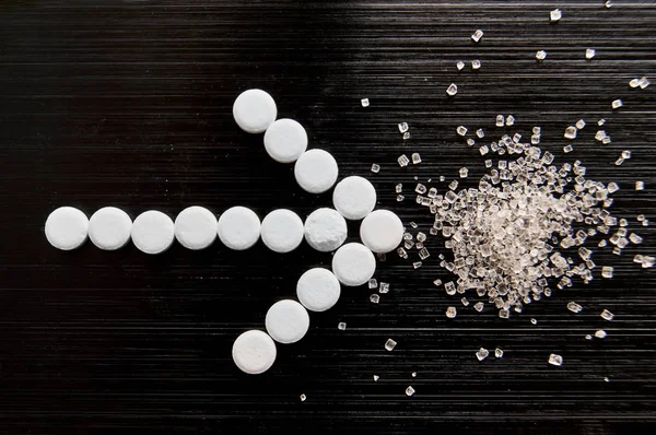 tatlandırıcı haplar koyu bir arka planda şekerle yatar.