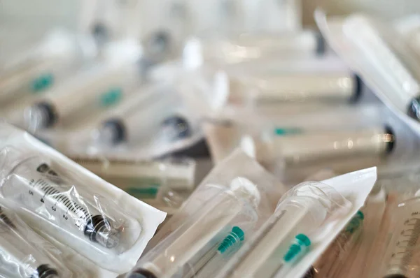 Bir paket açılmamış şırınga. Mühürlü şırıngalar desenli bir yüzeyde yatıyor..