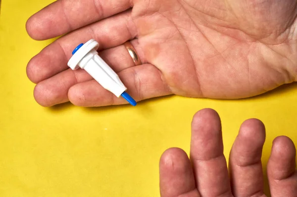 A diabetic checks his blood sugar. Close up man hands self-tested with a Lancet and a glucometer at home