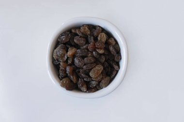 Kuru üzümler beyaz tencerede izole edilmiş.