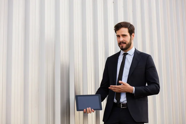 Schöner eleganter Mann im Anzug präsentiert den Bildschirm seines Tablets — Stockfoto