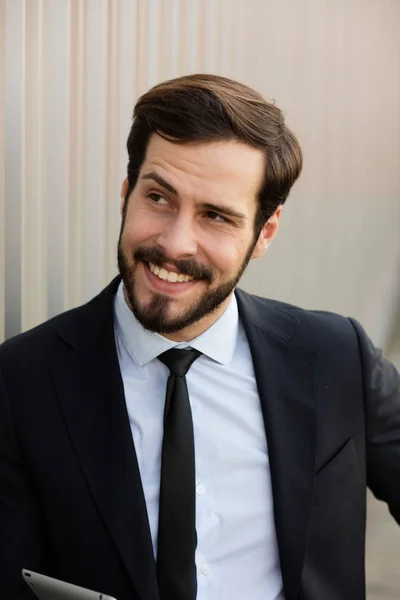 Un hombre de negocios sonriente con una tableta gris —  Fotos de Stock