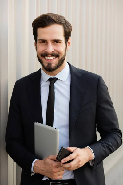 Uśmiechający się biznesmen z telefonów komórkowych i tabletów — Zdjęcie stockowe
