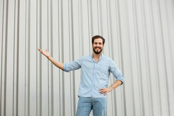 Pohledný mladý muž s vousy na šedém pozadí — Stock fotografie