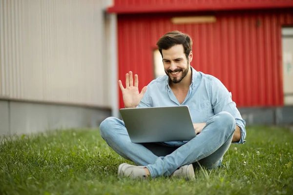 Ung man i casual jeans outfit liggande med sin laptop i f — Stockfoto