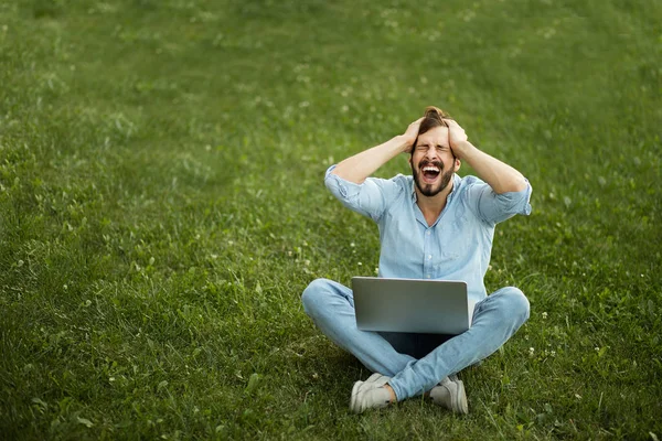 Giovane uomo in jeans casual vestito sdraiato con il suo computer portatile in f — Foto Stock