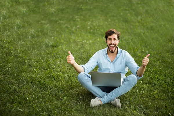 Jonge man in casual jeans outfit liggen met zijn laptop in f — Stockfoto