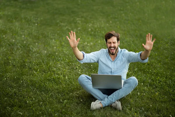 Giovane uomo in jeans casual vestito sdraiato con il suo computer portatile in f — Foto Stock