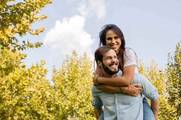 Gelukkige paar plezier buiten, de man met zijn vriendin op zijn rug — Stockfoto