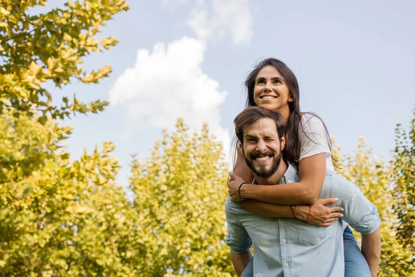 Coppia felice divertirsi fuori, l'uomo che trasporta la sua ragazza sulla schiena — Foto Stock