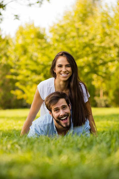 Sonriente mujer acostada en su amante fuera en hierba — Foto de Stock