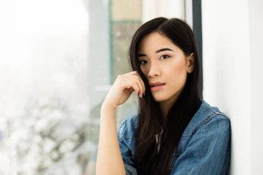 Asyalı kız yerde bir pencere yanında oturan