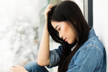 Asyalı kız yerde bir pencere yanında oturan