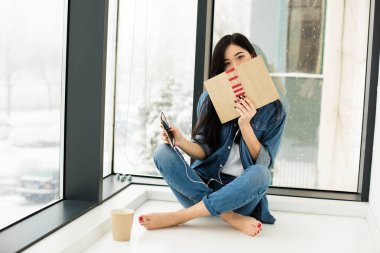 Asyalı kadın büyük pencereler yanında bir kitap okuma