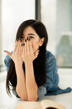 Asyalı kadın büyük pencereler yanında bir kitap okuma