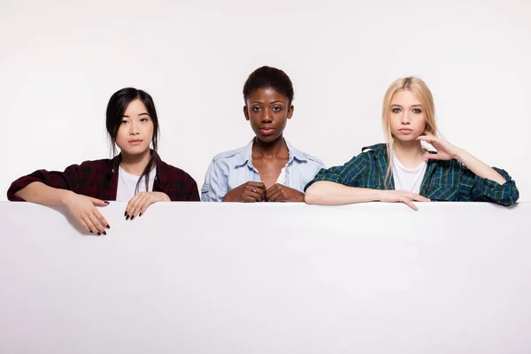 Tři různé etnické dívky opírající se o bílém panelu — Stock fotografie