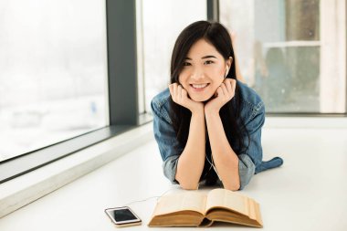 Asyalı kadın büyük pencereler yanında bir kitap okuma