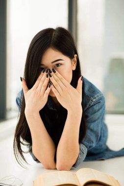 Asyalı kadın büyük pencereler yanında bir kitap okuma