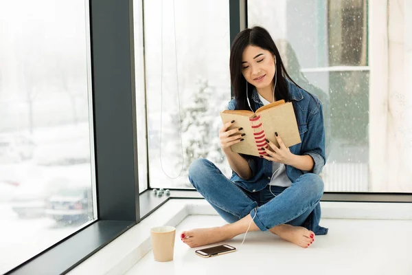 Asyalı kadın büyük pencereler yanında bir kitap okuma — Stok fotoğraf